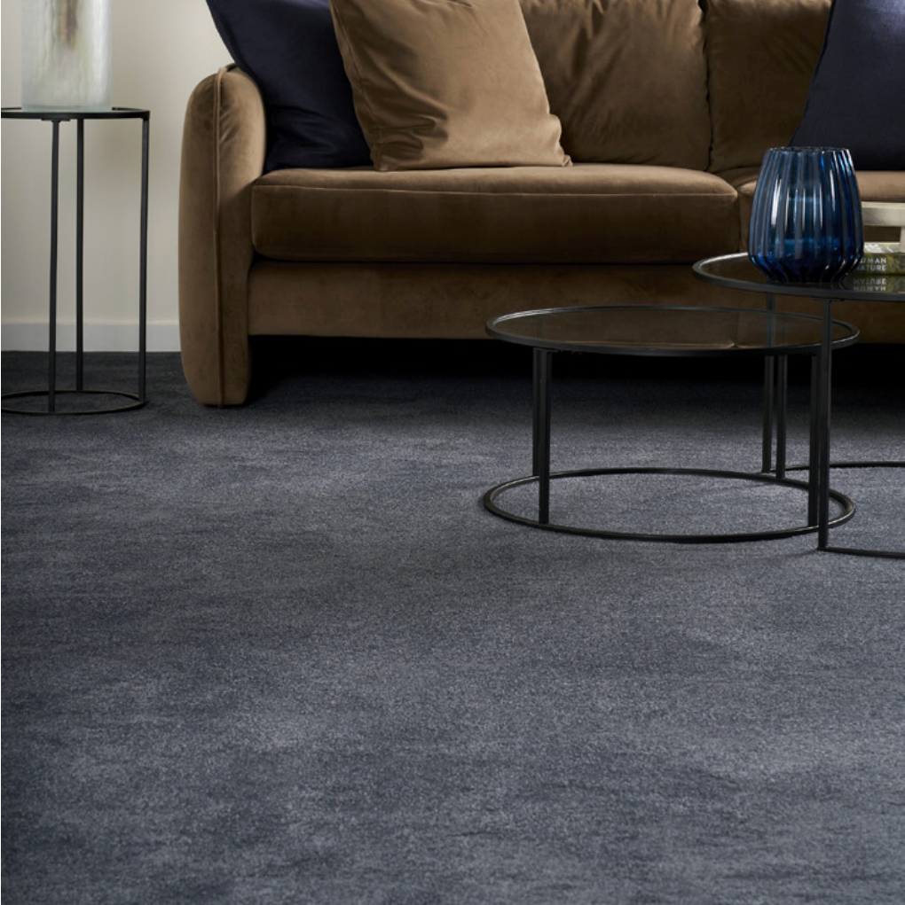 Living room with a brown sofa, round glass coffee table, and charcoal carpet